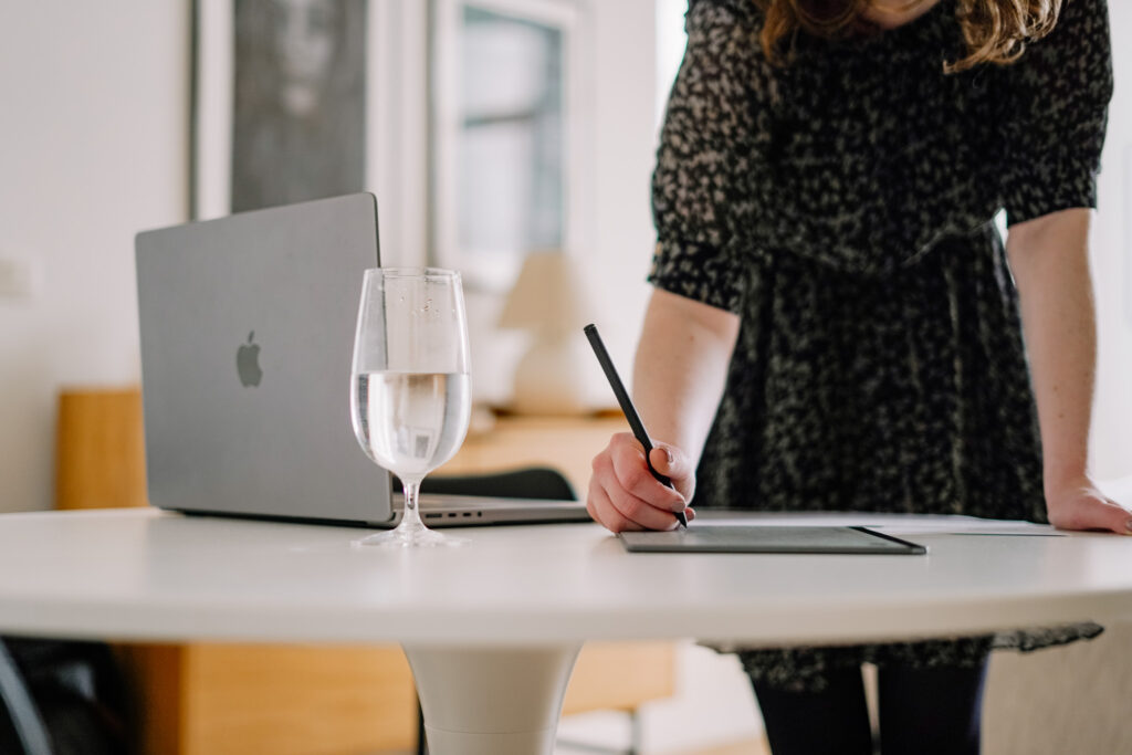 Creative entrepreneur writing on a reMarkable tablet next to a MacBook on a white desk