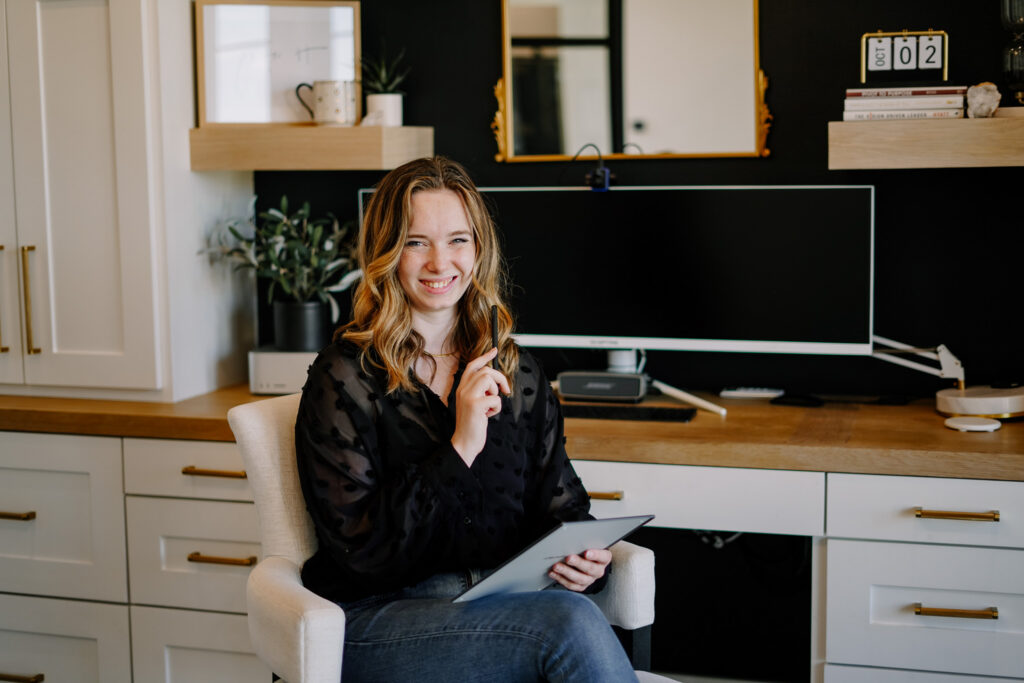 Gillian Sarah sitting in a modern office writing on a digital notepad smiling